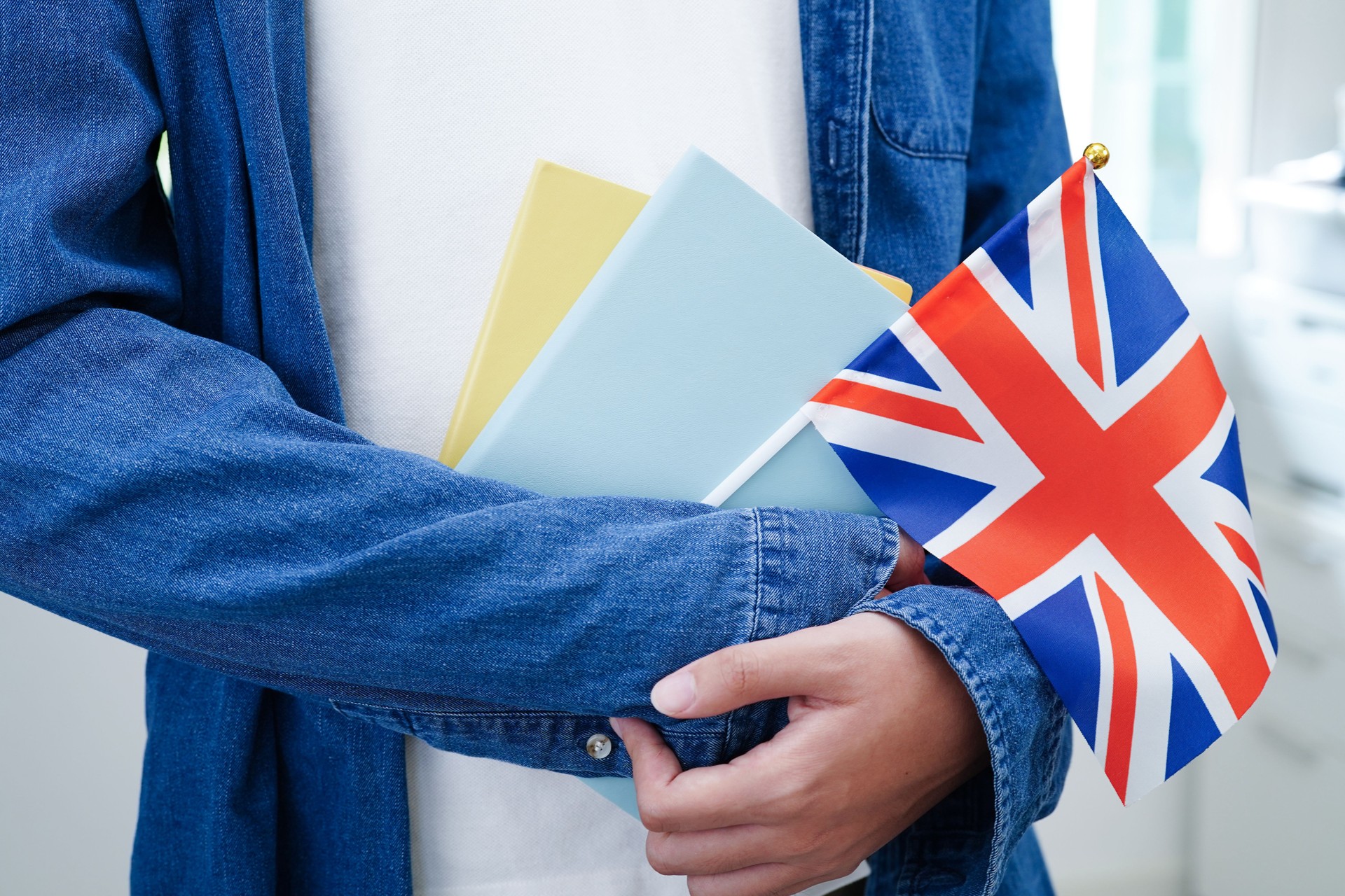 Learning English, Asian teenage student holding book with flag for language program education.